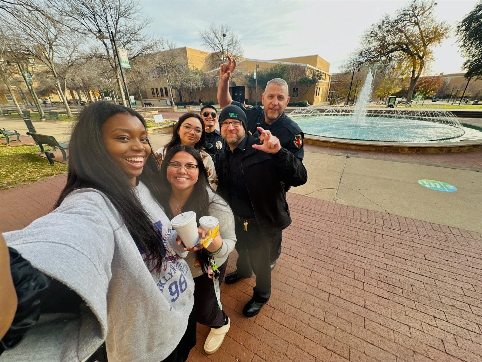 Selfie-style photo with students and two police officers lined up outside of UNT's Willis Library