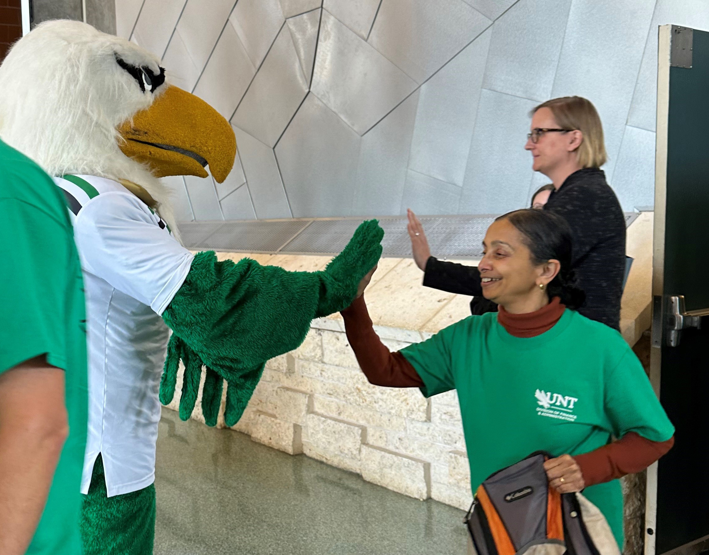 A staff member gives a high five to mascot Scrappy