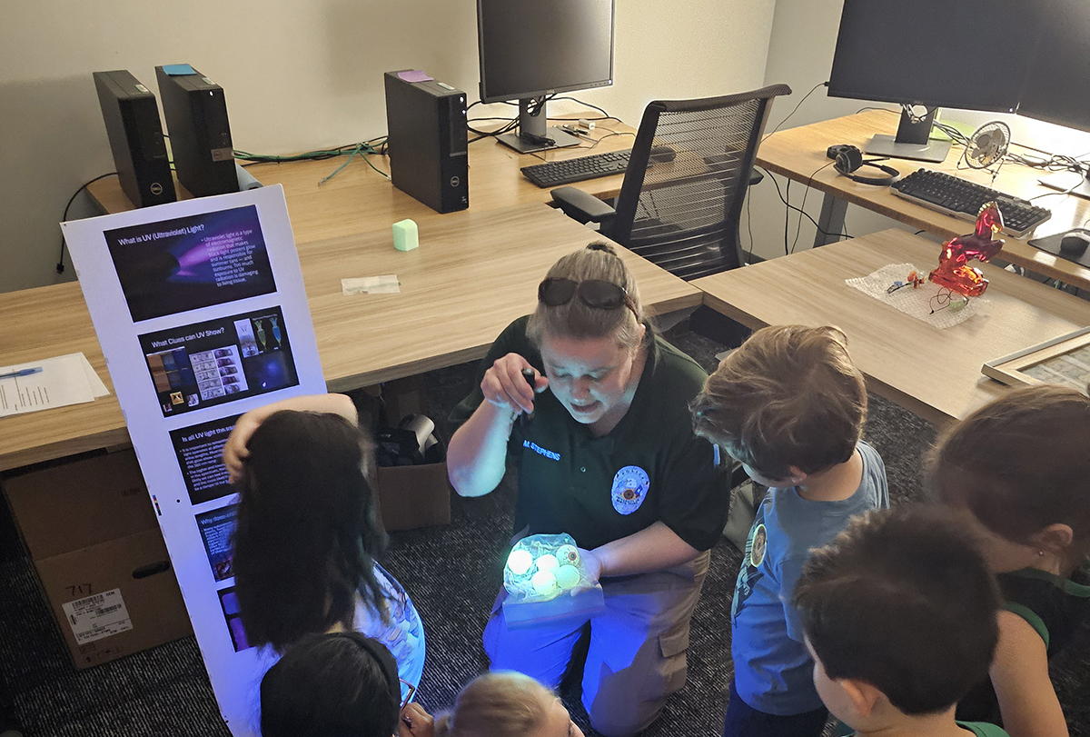 police officer showing children how to uncover evidence with a blacklight