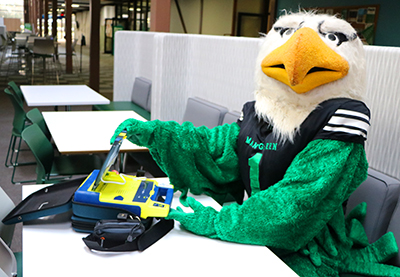 Scrappy sitting at table with an automatic external defibrillator