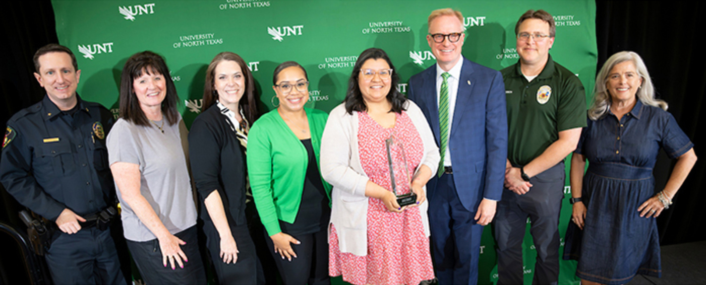 Seven staff members stand with President Keller as they receive the Look North Outstanding Team Award.