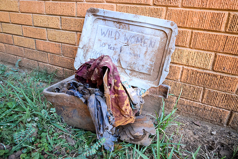 dirty tub with clothing and other memorabilia by a brick wall