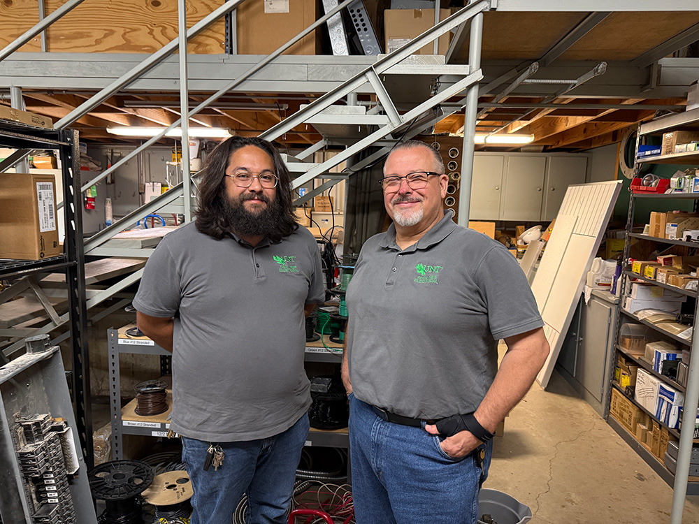 Jeff Moralde and Jon Shaw standing in the electrical unit shop