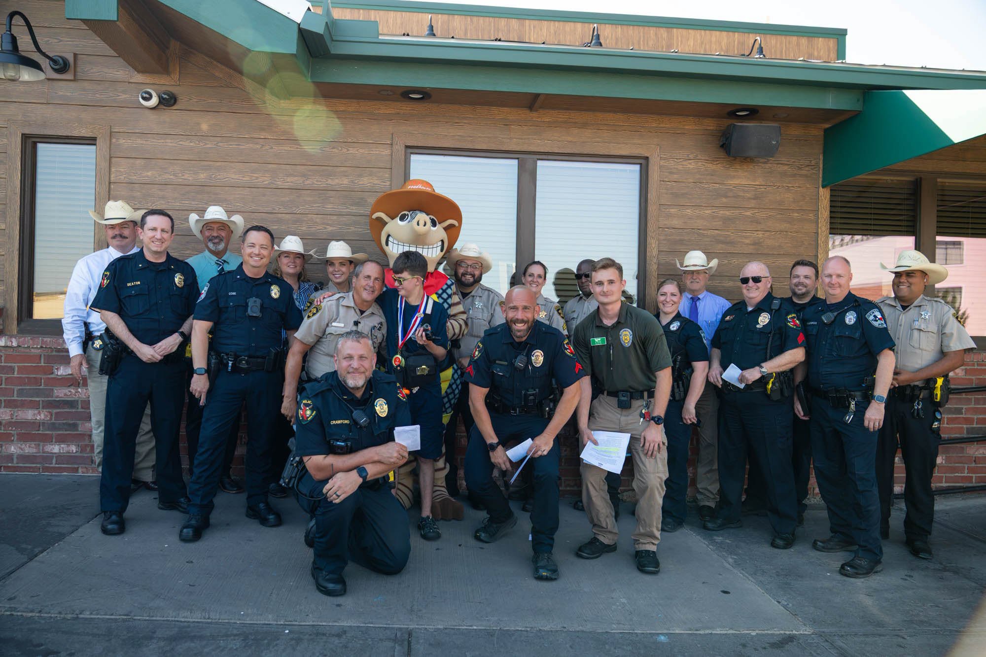 Law enforcement officers pose outside a restaurant.