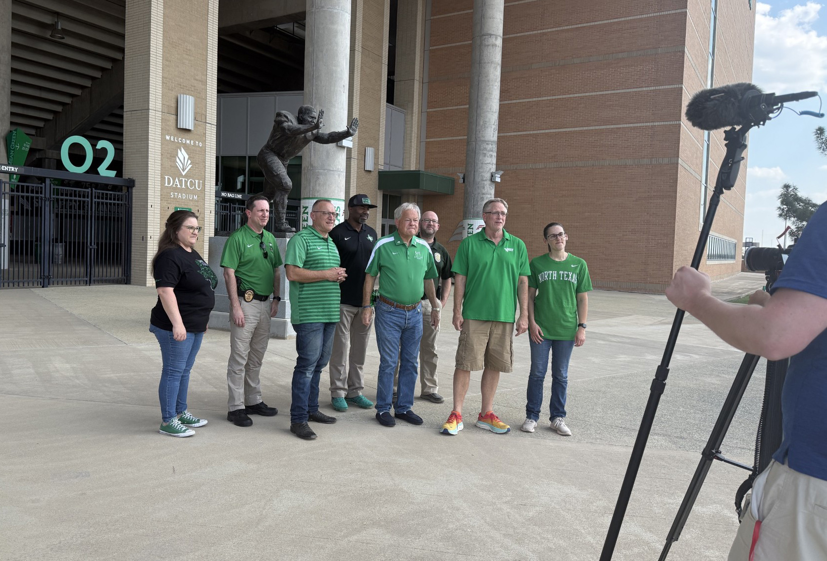 UNT and city officials standing outside the DATCU Stadium near a statue of alumnus Joe Greene.
