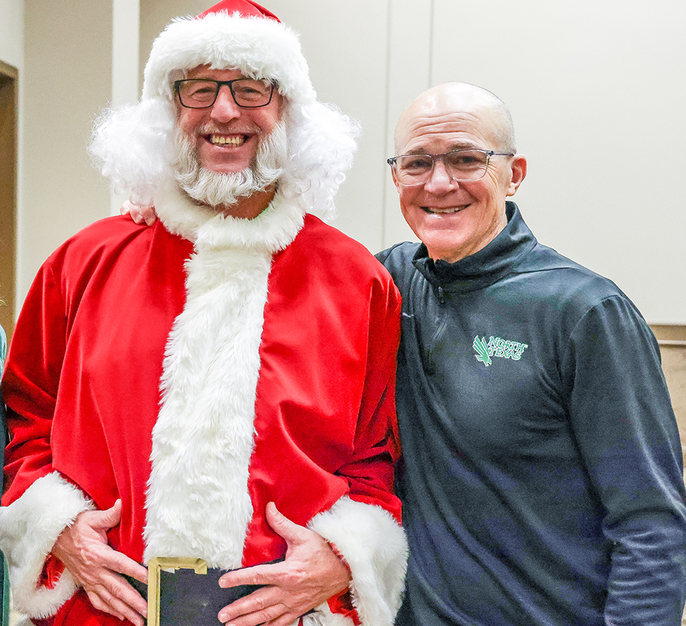 An image of a person dressed as Santa standing next to the department associate vice president