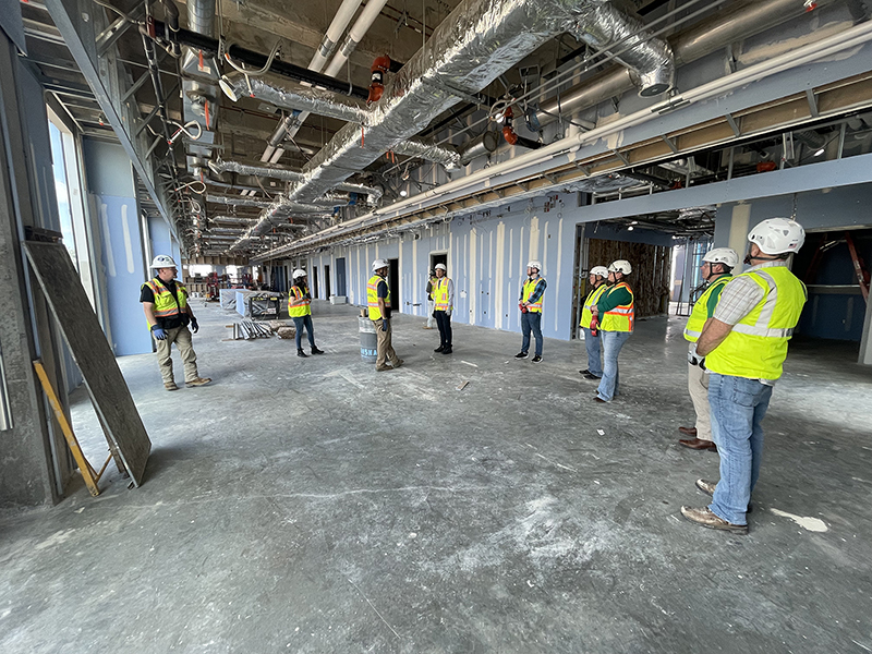 people with hard hats and safety vests inside an unfinished building