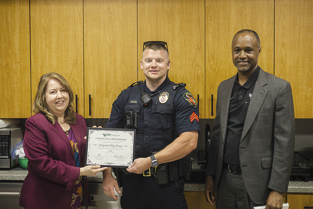 Sergeant Riley Dixon stands between UNT's Chief HR Officer and Vice President Clayton Gibson