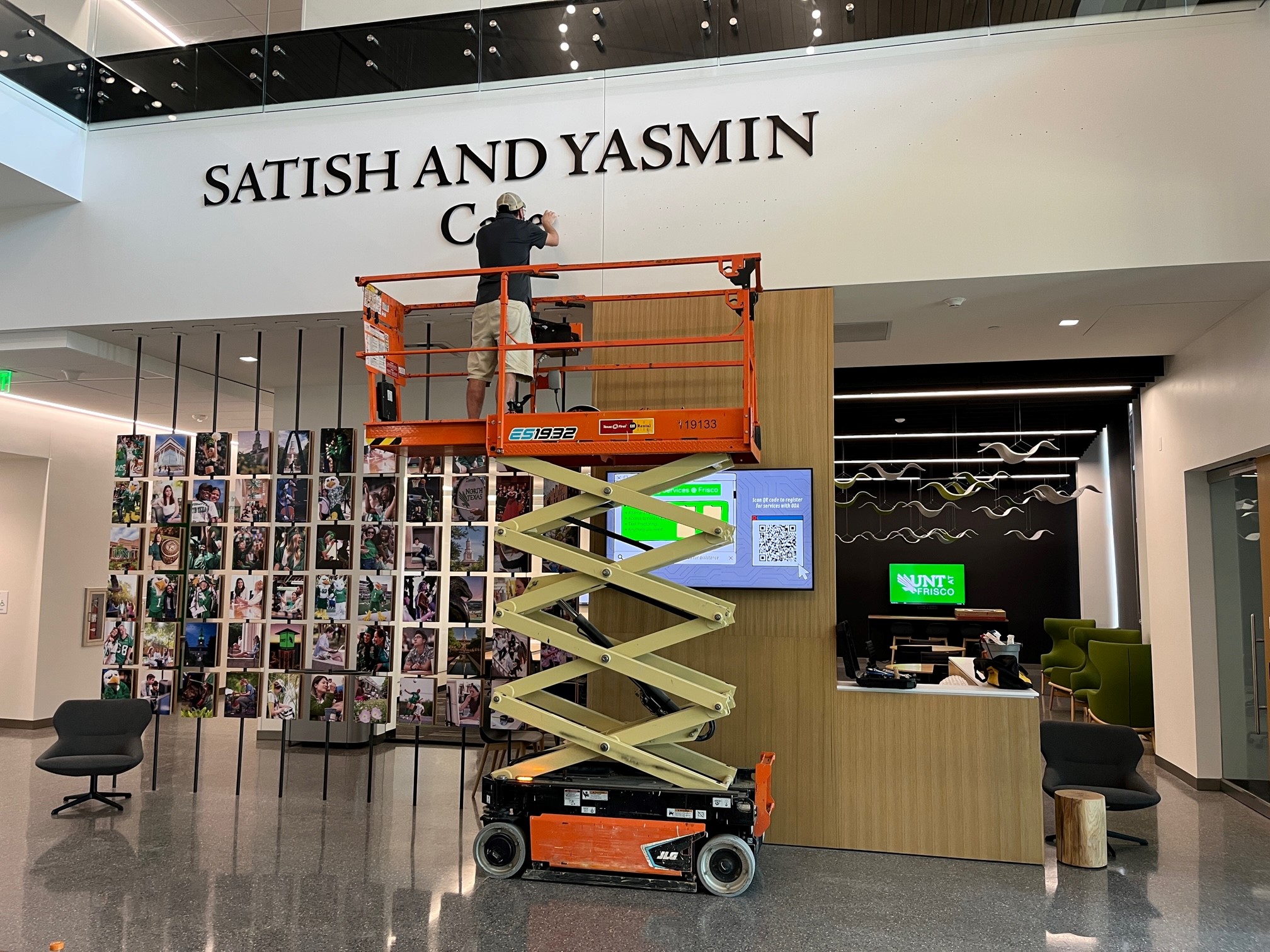 A Facilities staff member on an aerial platform installing a sign.